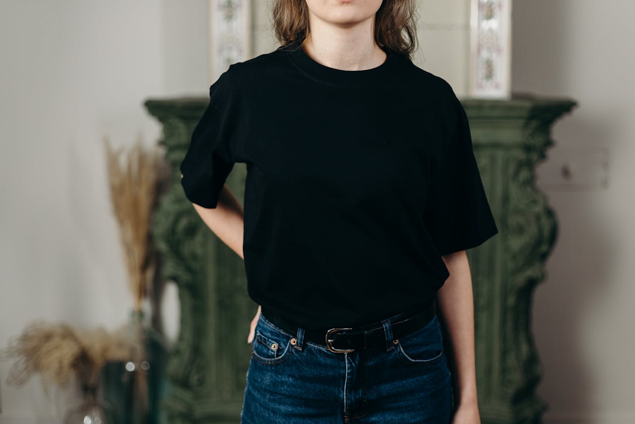 Mastering the First Impression: Your intriguing post title goes here Faceless model in black t-shirt and jeans showcasing minimalist fashion style indoors.
